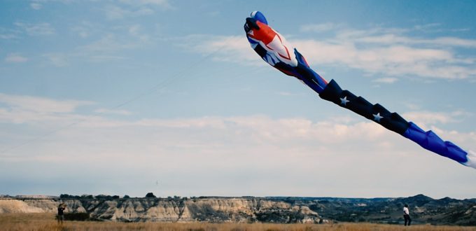 A large, tubular, red, white and blue kite flies over the badlands during Medora’s Annual Hot Air Balloon Rally and Kite Festival.