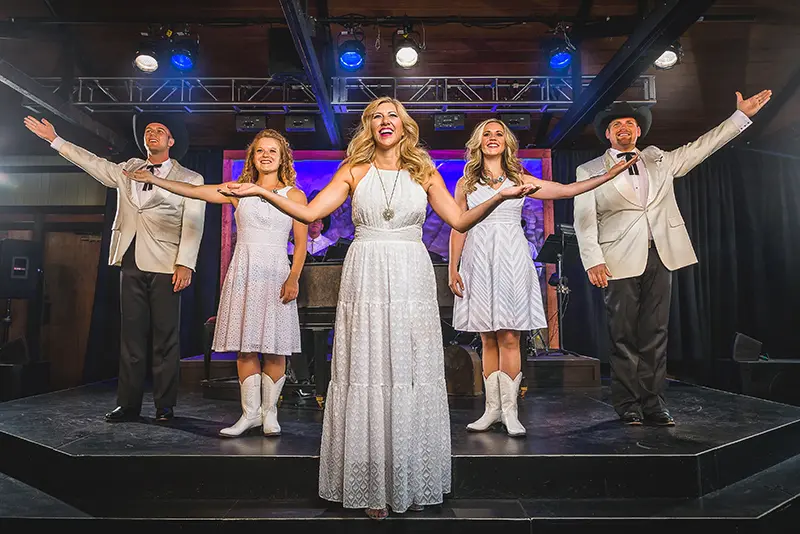 Five singers dressed in white raise their arms singing in the Medora Gospel Brunch in Medora, North Dakota.