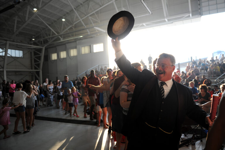 Theodore Roosevelt reprisor Joe Wiegand waves to a full crowd in Medora, ND