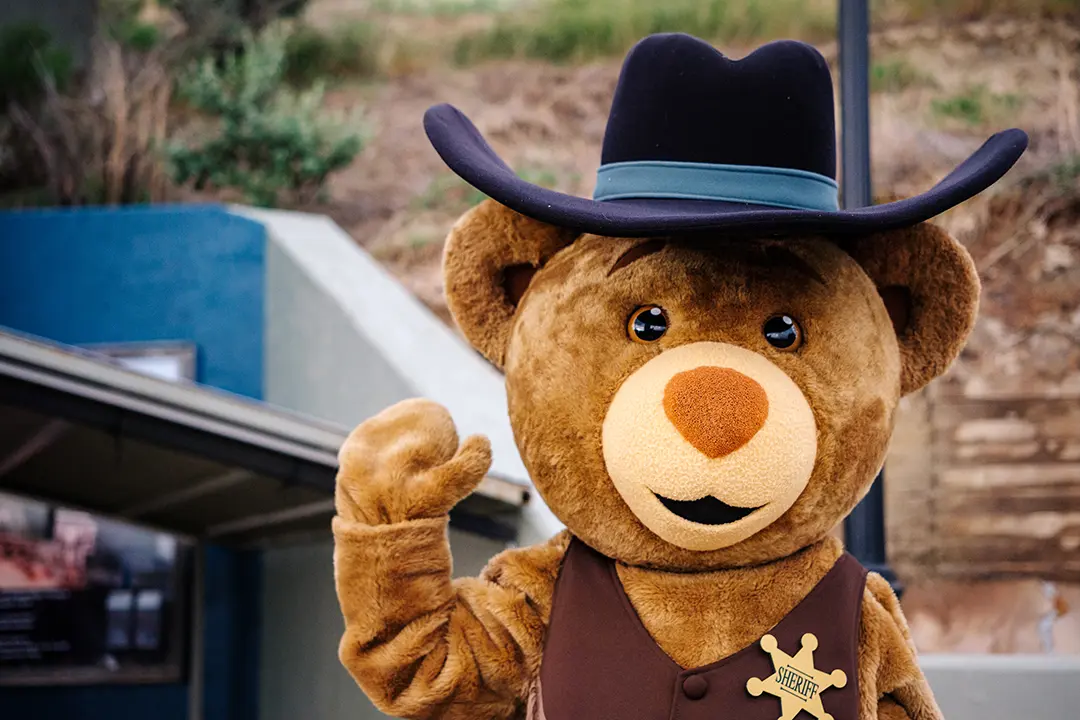Sheriff Bear a mascot for the Medora Musical stands at the Burning Hills Amphitheatre and waves. The character can be found at many popular attractions in Medora, North Dakota.