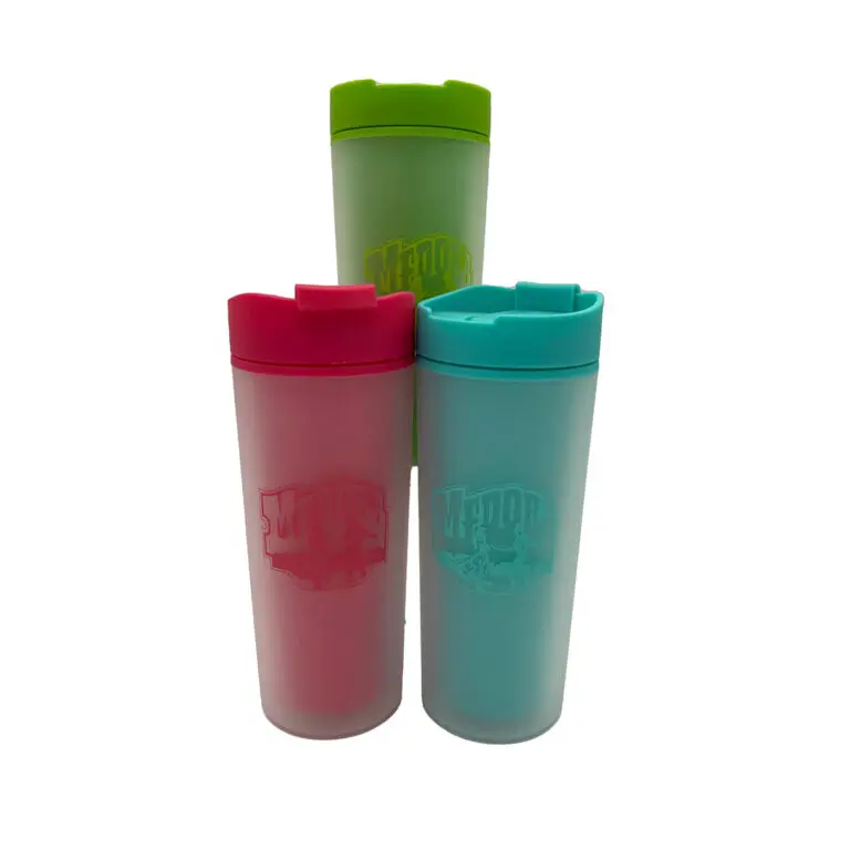 Three tumblers sit in a pyramid. The cups all have a logo with two dancers and the text "Medora" embossed. The cups are red, green, and teal. These cups are available at stores in Medora, North Dakota