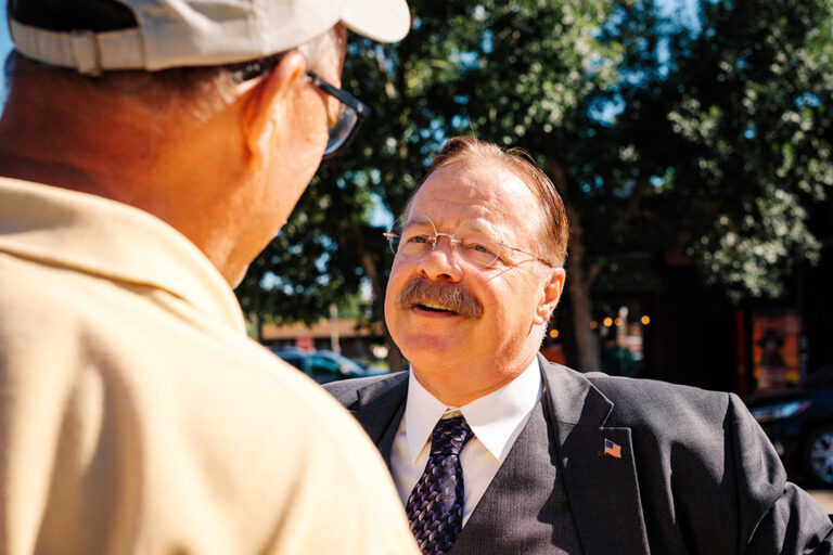 Joe Wiegand, a Theodore Roosevelt reprisor, stands in downtown Medora, North Dakota talking to a man after a show in Medora, North Dakota
