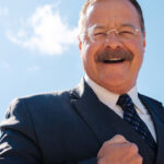 Joe Wiegand, a Theodore Roosevelt Reprisor, poses against blue skies with a smile in Medora, North Dakota