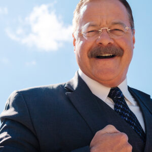 Joe Wiegand, a Theodore Roosevelt Reprisor, poses against blue skies with a smile in Medora, North Dakota