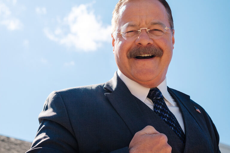 Joe Wiegand, a Theodore Roosevelt Reprisor, poses against blue skies with a smile in Medora, North Dakota