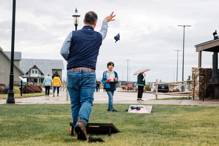 A man tosses a bean bag as he plays a game of cornhole with his son on the lawn at the Pitchfork Steak Fondue, a dining attraction in Medora, North Dakota