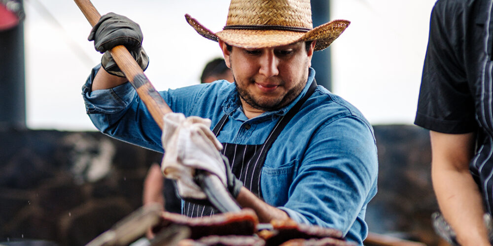 A chef in a cowboy hat holds a pitchfork loaded up in steaks and serves them at the Pitchfork Steak Fondue, a dining attraction in Medora, North Dakota