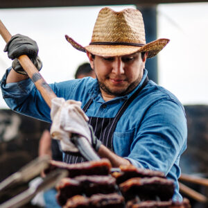 A chef in a cowboy hat holds a pitchfork loaded up in steaks and serves them at the Pitchfork Steak Fondue, a dining attraction in Medora, North Dakota