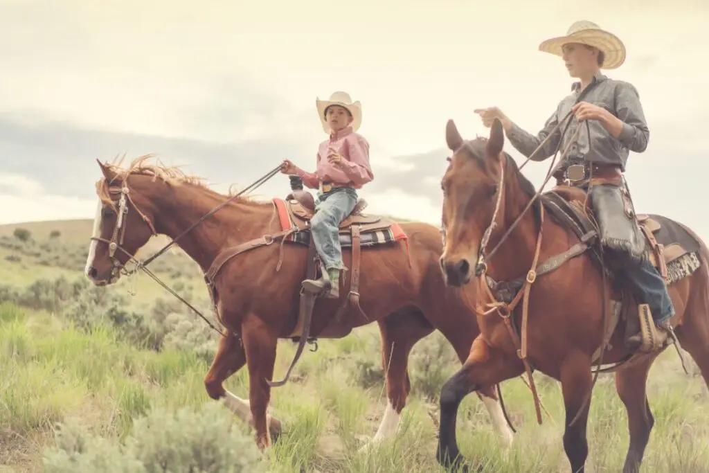 Two young people ride on horses through the Badlands