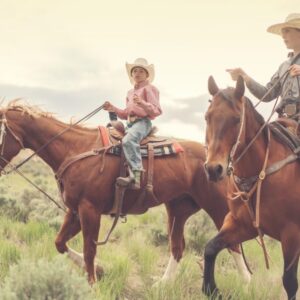 Two young people ride on horses through the Badlands