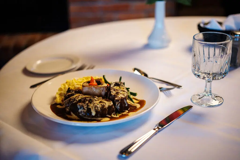 A plate of Bison Osso Bucco set on a table in Theodore's Dining Room, a gourmet restaurant in Medora, North Dakota