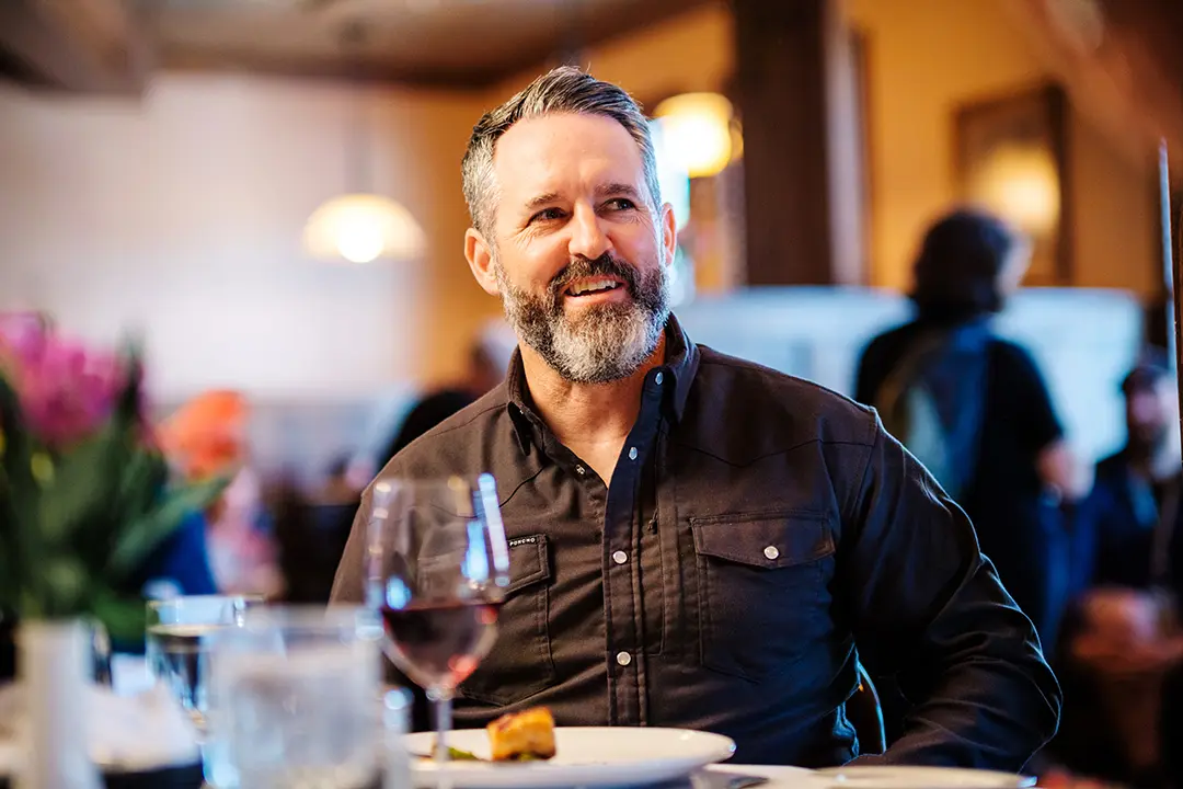 A man sits at a table with a plate of food and glass of wine in Theodore's Dining Room, a high-end restaurant in Medora, North Dakota