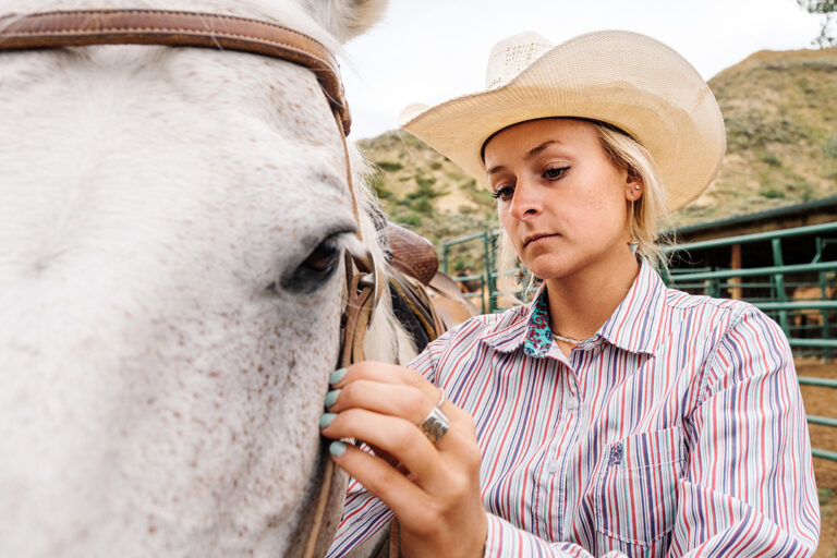 A women adjusts equipment on a horse at riding stables in Medora, North Dakota