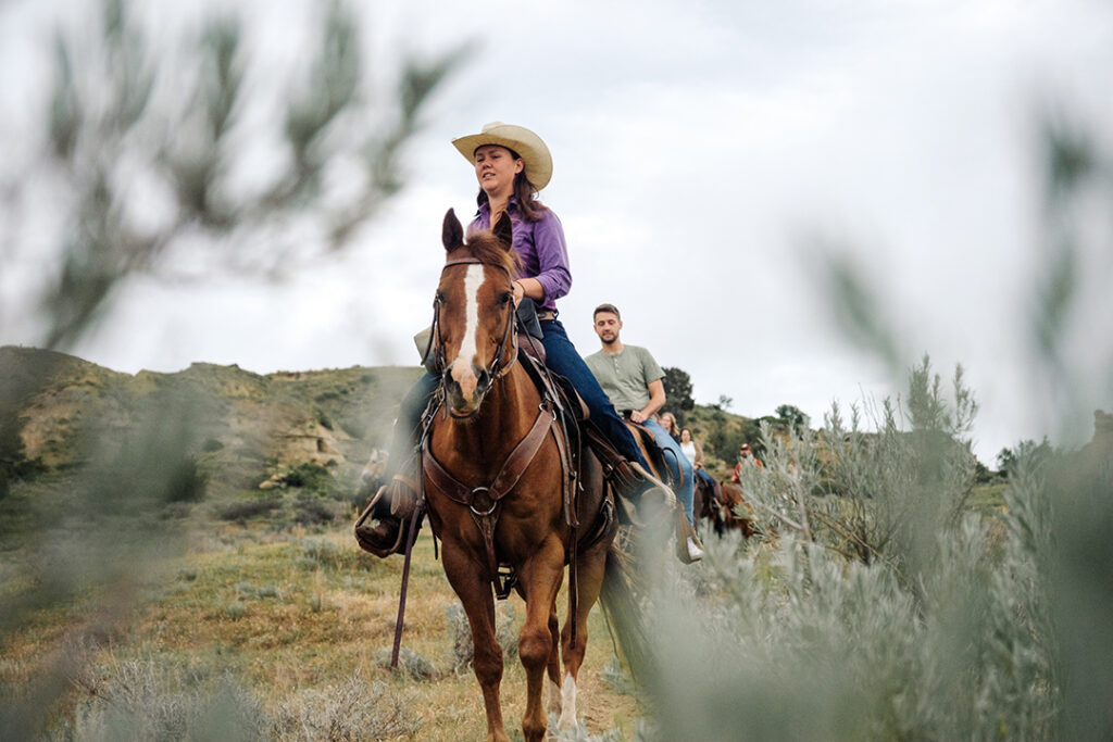 A women sits on a horse and leads a trail ride through Medora, North Dakota