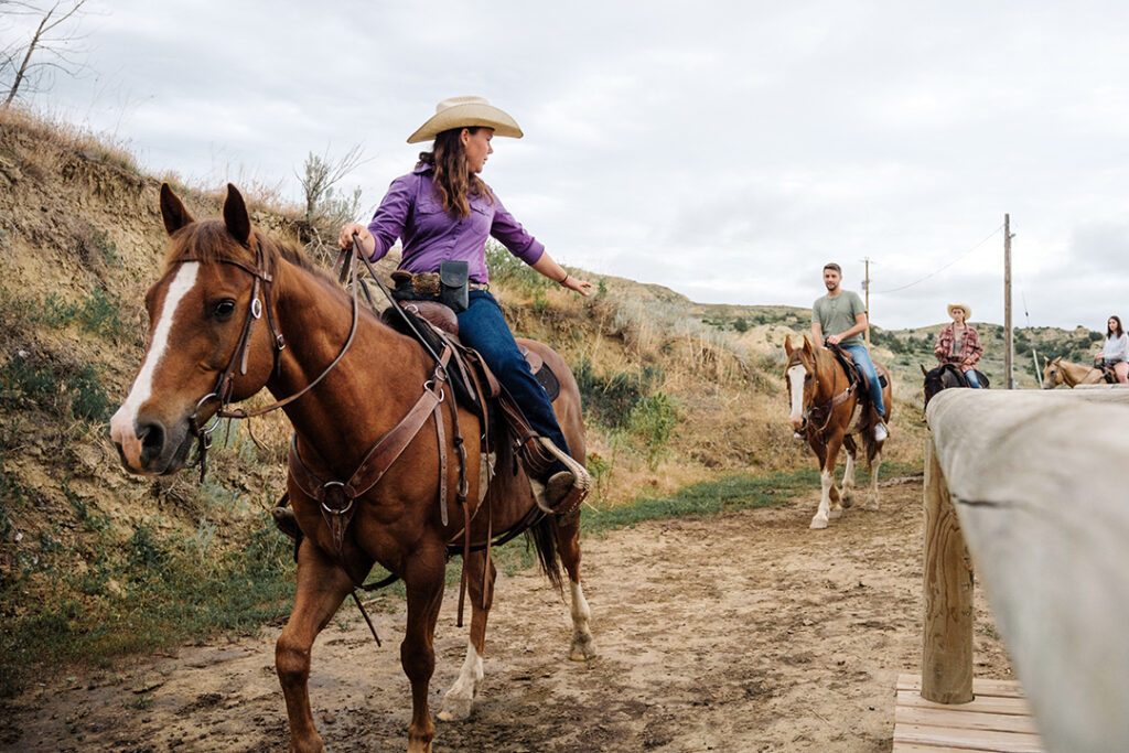 A women sits on a horse and guides other riders on a trail ride in Medora, North Dakota