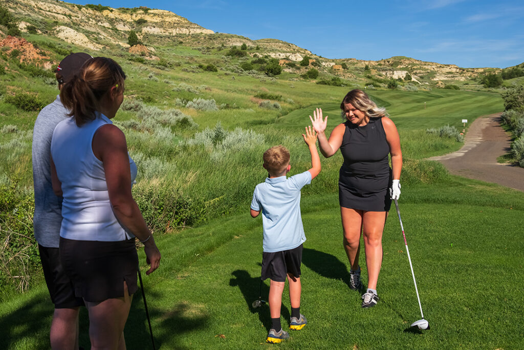 A family on the course at Bully Pulpit Golf Course in Medora, North Dakota - a golf course in the North Dakota Badlands with free tee times and golf for kids