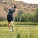 A golfer tees off on the course at Bully Pulpit Golf Course in Medora, North Dakota - a golf course in the North Dakota Badlands