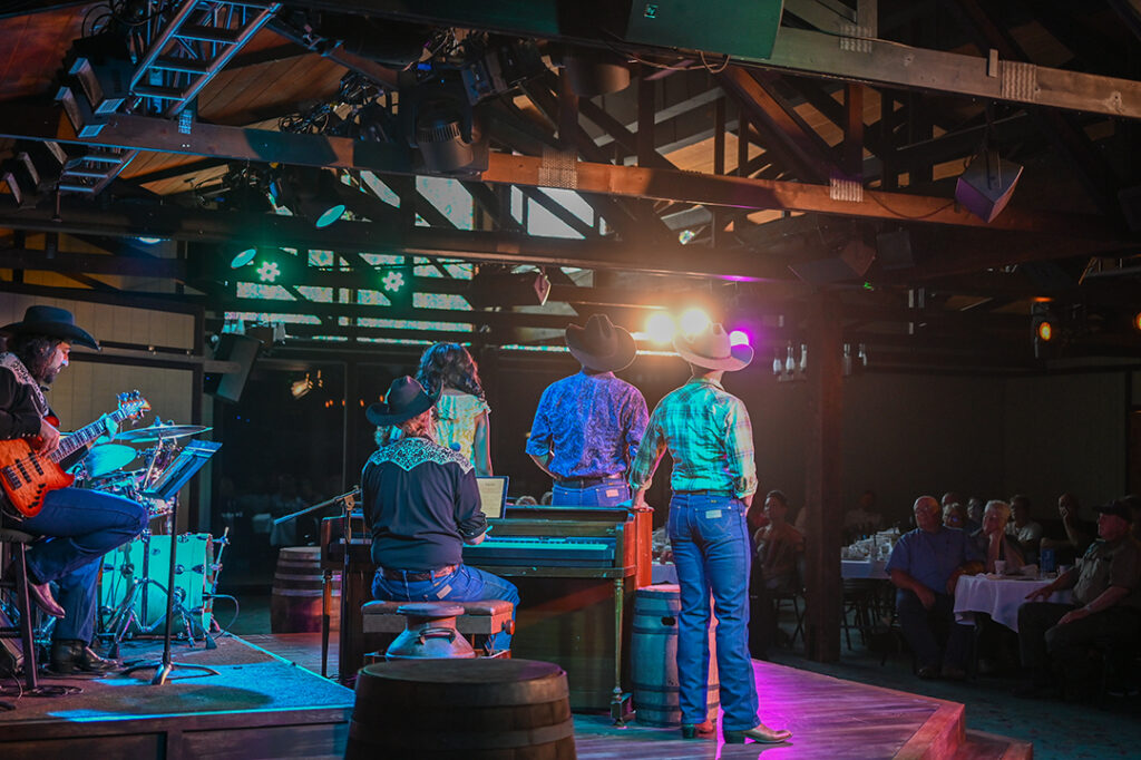 Actors stand dramatically lit in the spotlight facing the audience while performing in the Medora Gospel Brunch.