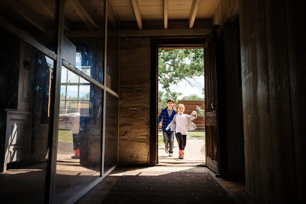 Two children run through the front door, into Theodore Roosevelt's historic cabin in Medora, ND.