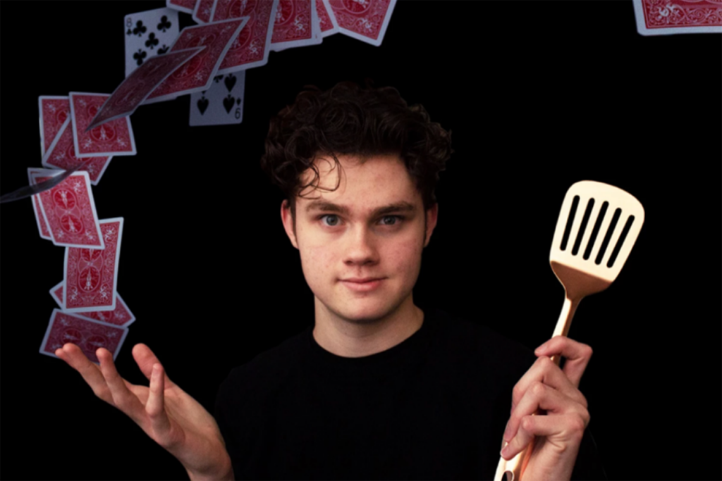 Colin Zasadny, the star of the Medora Magic Show magician poses with a spatula as cards fly above him.