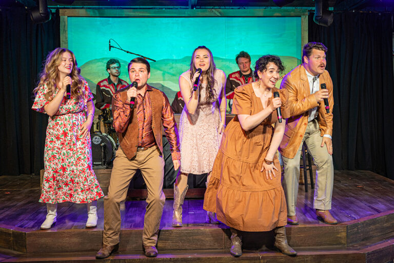 A group of singers hold microphones and sing on stage as a band plays behind them at the Medora Gospel Brunch, a popular entertainment attraction in Medora, North Dakota