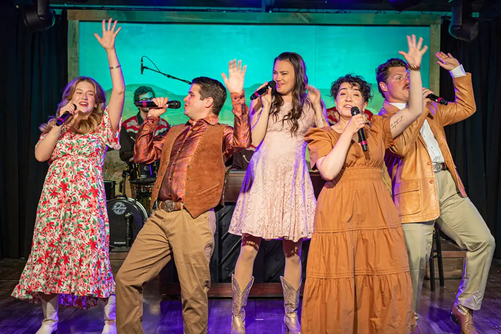 A group of singers hold microphones and lift their hands in praise on stage at the Medora Gospel Brunch, a popular entertainment attraction in Medora, North Dakota