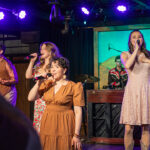 Four singers stand on stage and sing into microphones at the Medora Gospel Brunch, a popular entertainment attraction in Medora, North Dakota