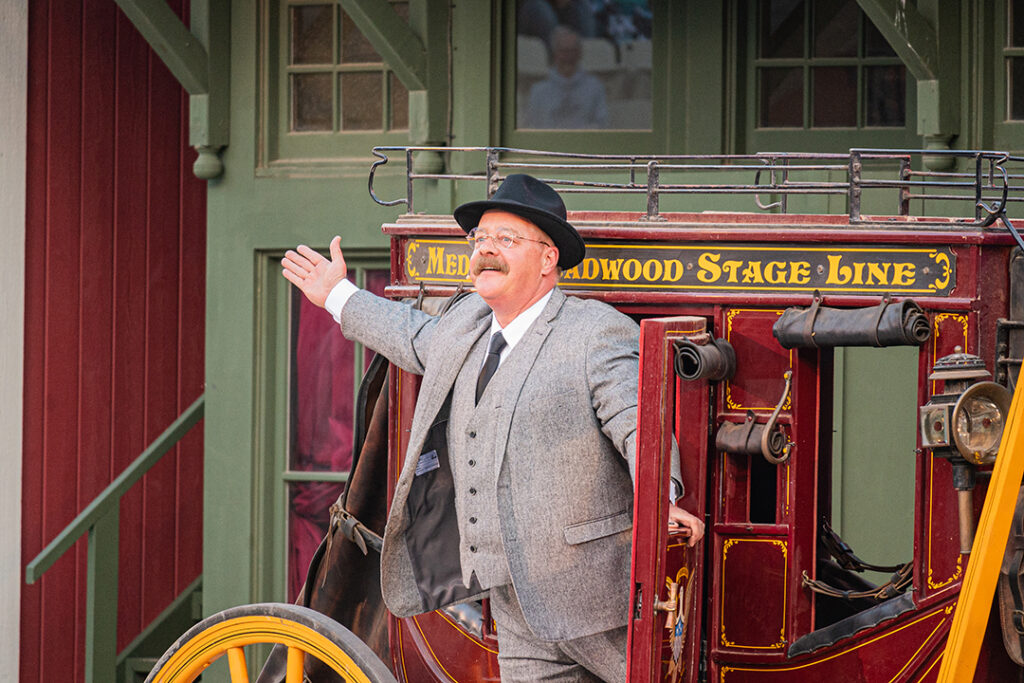 A man dressed as Theodore Roosevelt stands with his arm outstretched from a horse-drawn stagecoach on stage at the Medora Musical, a popular entertainment attraction in Medora, North Dakota