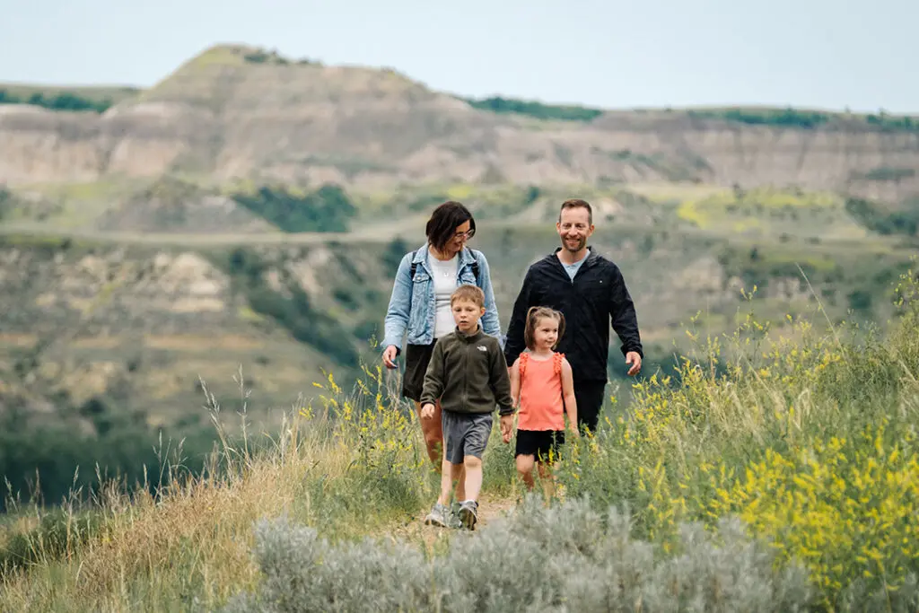 A family hikes on a trail with wildflowers and sage through the badlands of Theodore Roosevelt National Park a popular outdoor attraction in Medora, North Dakota