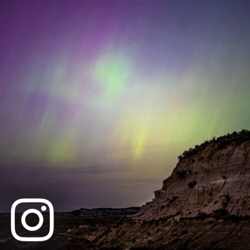 Purple and green northern lights streak across the North Dakota Badlands, Theodore Roosevelt National Park, Medora, ND