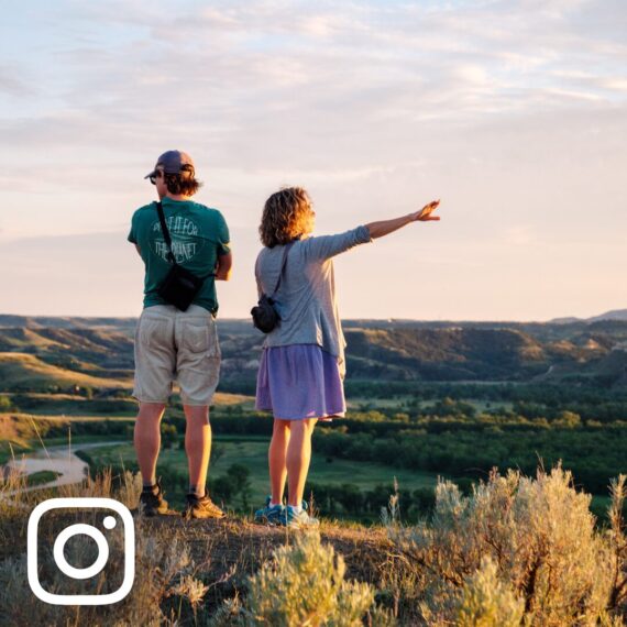 two hikers point across a valley at sunset in the North Dakota Badlands, Theodore Roosevelt National Park, Medora, ND
