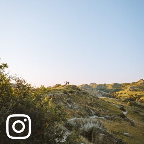 Four hikers stand on a distant hill in the North Dakota Badlands, Theodore Roosevelt National Park, Medora, ND