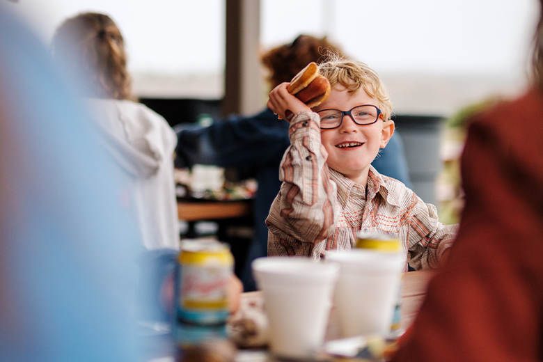 small boy eating at a park with a hotdog in his hand | Medora, ND Pitchfork Steak Fondue