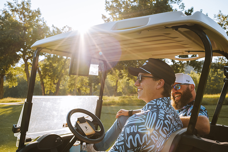 two people in a golf cart at Bully Pulpit Golf Course in Medora, ND