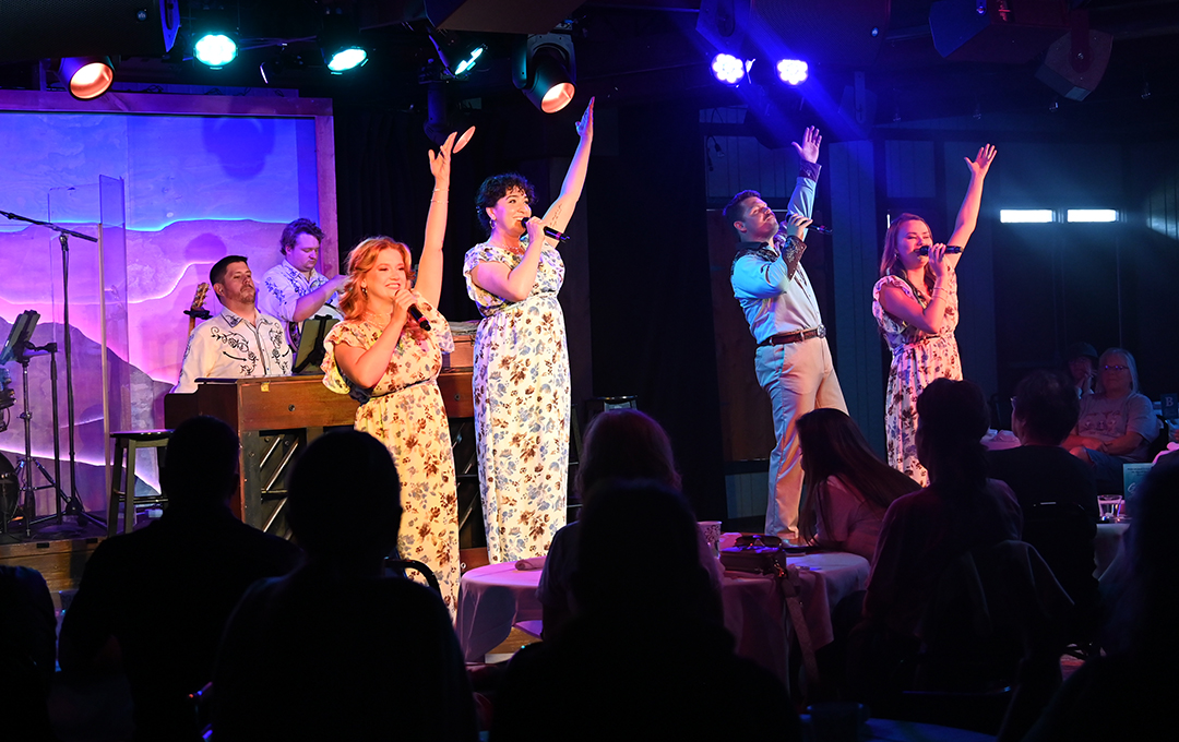 four performers on stage singing