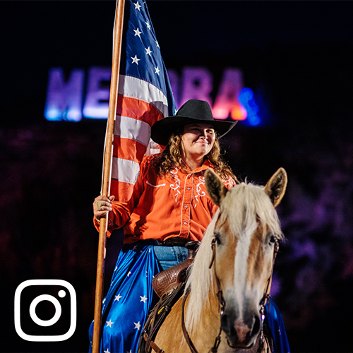 woman sitting horseback in Medora holding an American flag