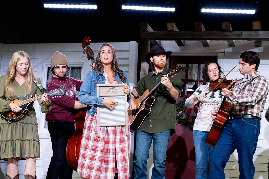 The cast of Medora Musical Christmas lined up on stage, each opkaying their instruments